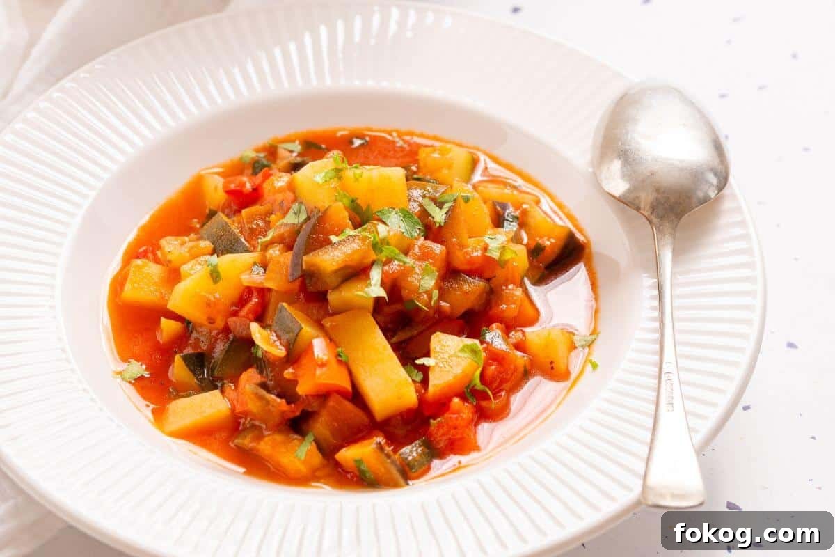 12 Irresistible Potato Recipes You’ll Love Making Again 7 A pot of Italian vegetable stew with a spoon, garnished with chopped green herbs, on a white tablecloth with a small bowl of parsley on the side.