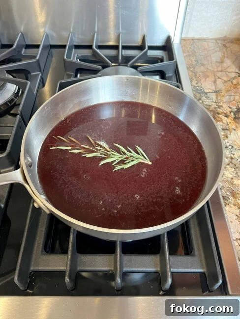 Pomegranate-Port Gravy with Rosemary for Roasts and Poultry 4 Pomegranate juice and broth and port and rosemary ready to reduce in a pot.