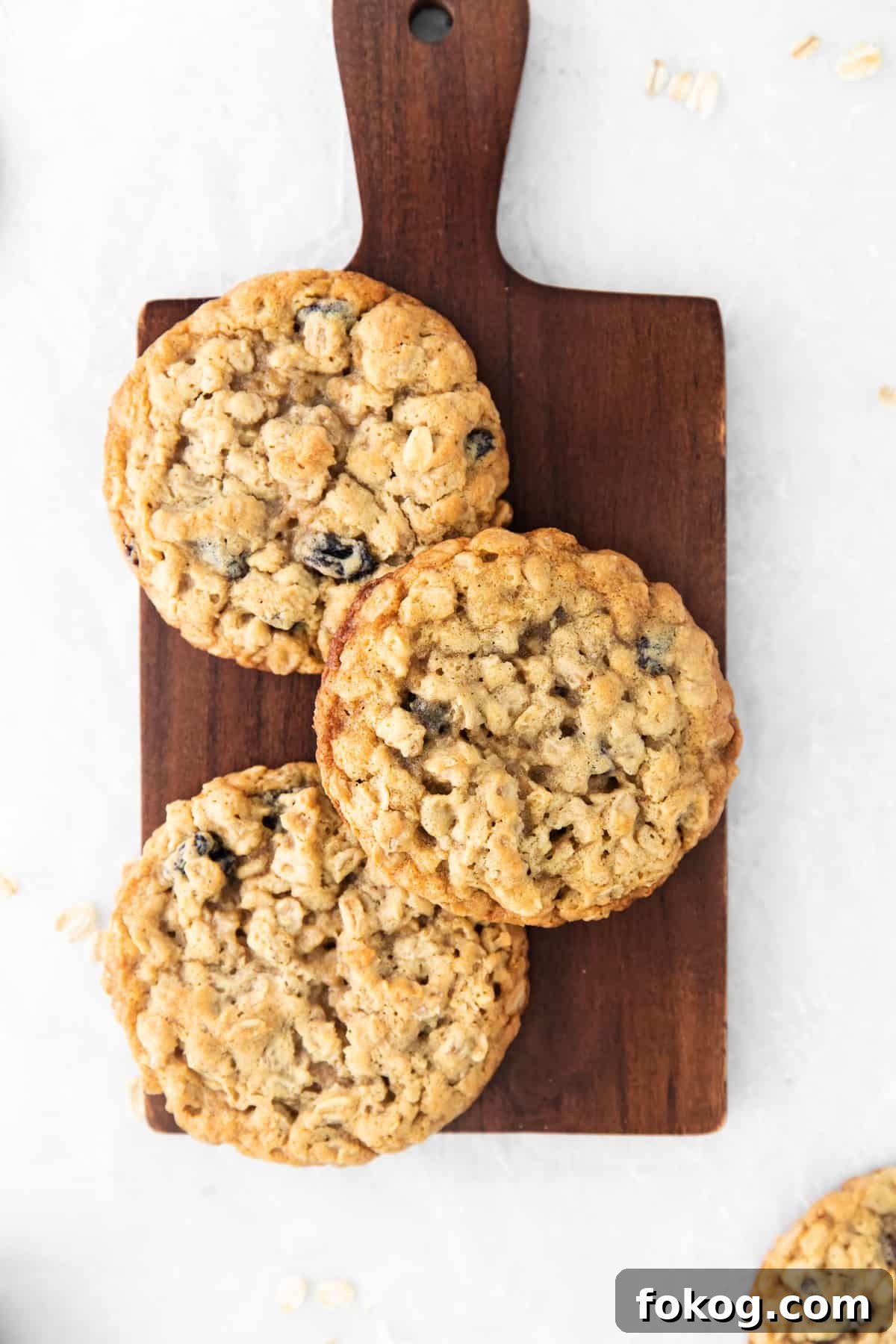 oatmeal raisin cookies on a wooden cutting board.