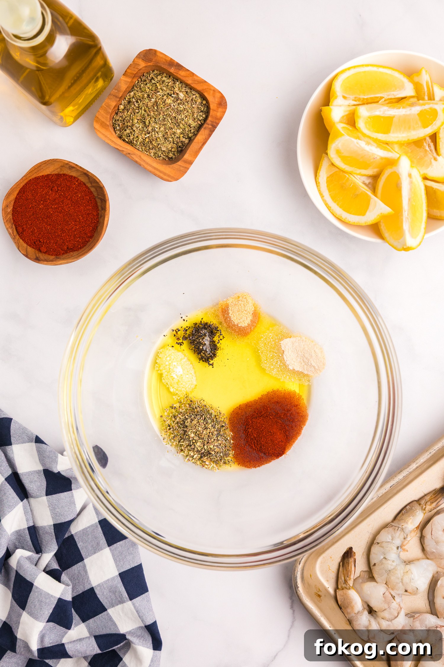 Perfect Grilled Shrimp Recipe for Juicy, Flavorful Results 4 A glass mixing bowl containing olive oil and a variety of spices including paprika, oregano, onion powder, garlic powder, salt, and pepper.