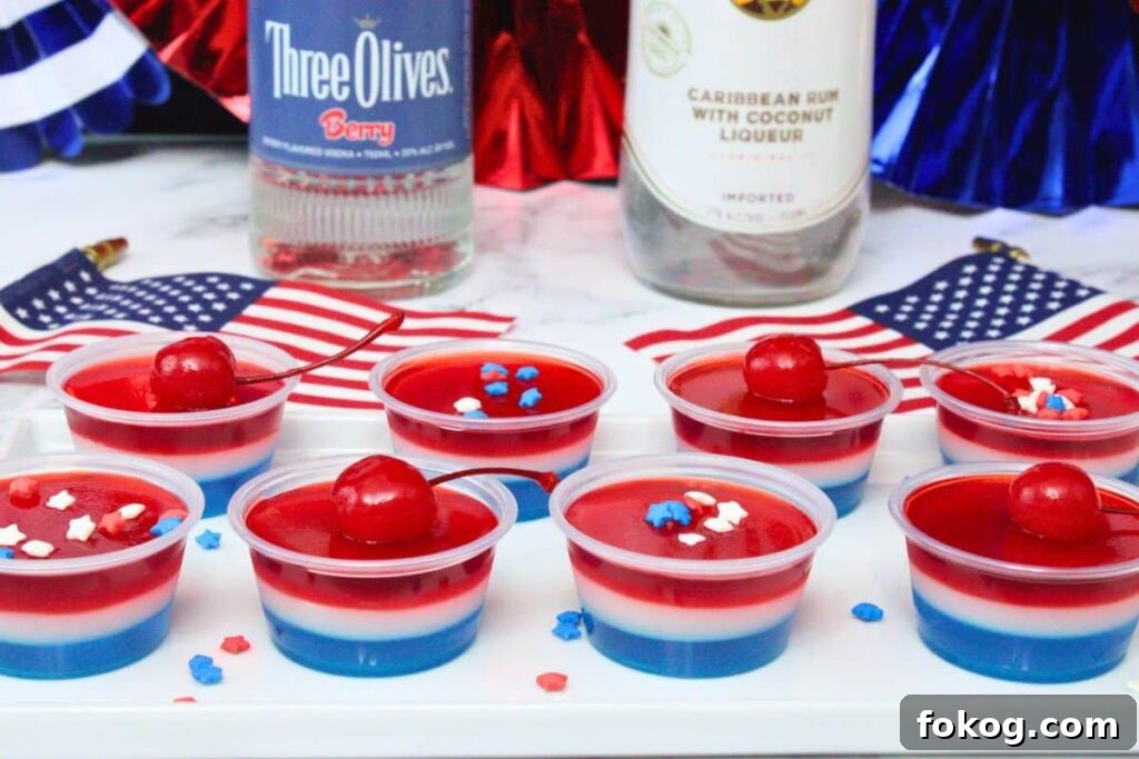several layered red white and blue jello shots in front of liquor bottles with small American flags