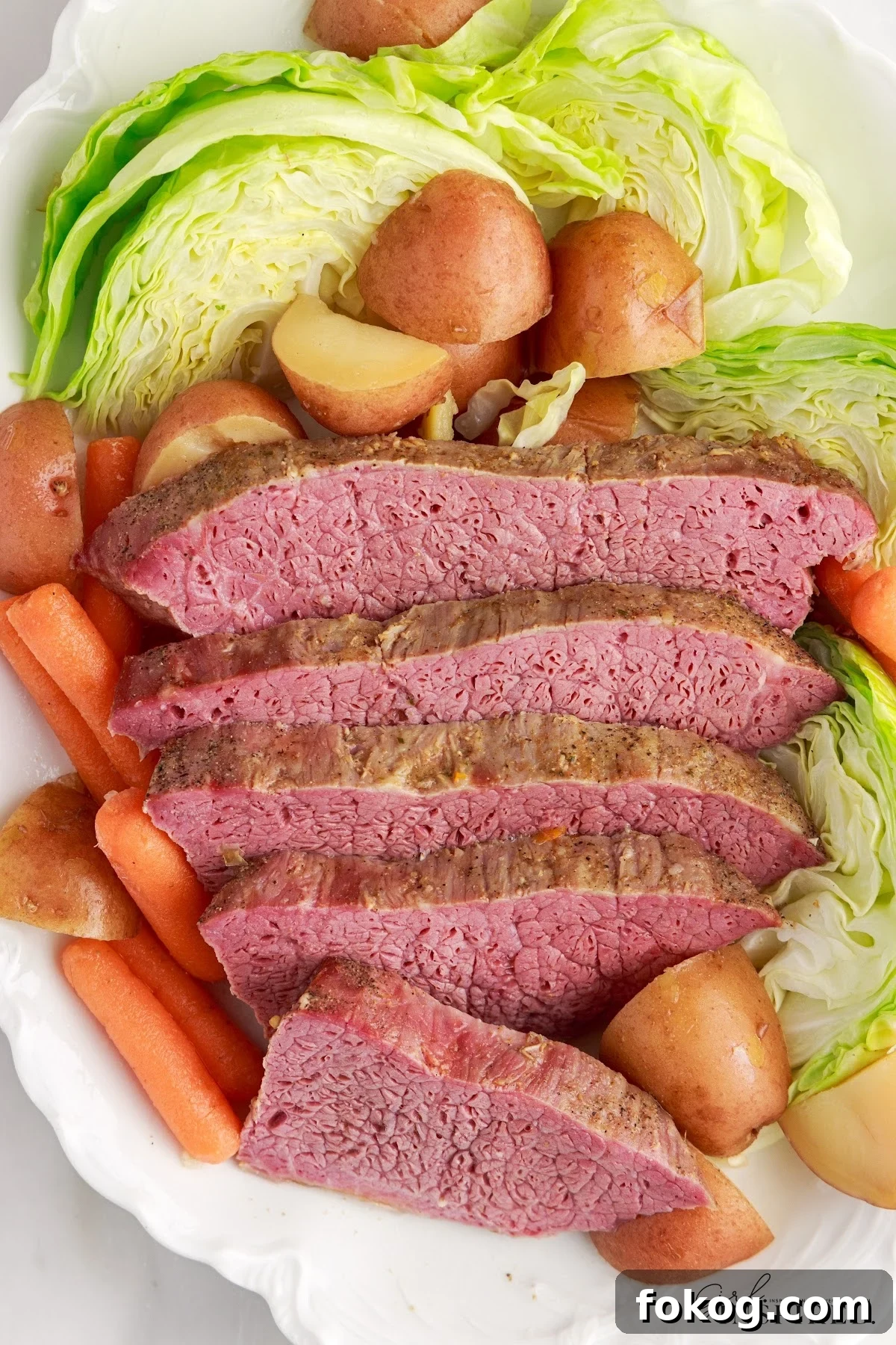 top view of Slow Cooker Corned Beef and cabbage on a platter, sliced along with cabbage, carrots and potatoes.