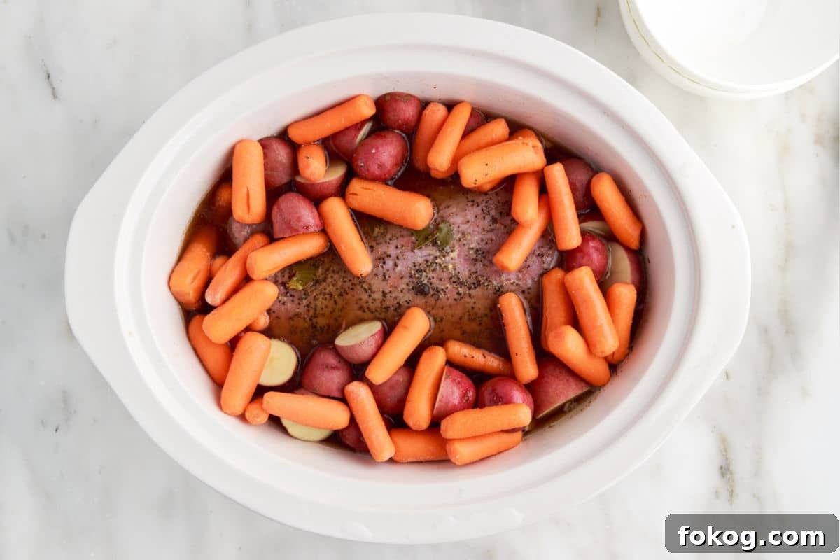 added carrots and potatoes into the crock pot to continue cooking.