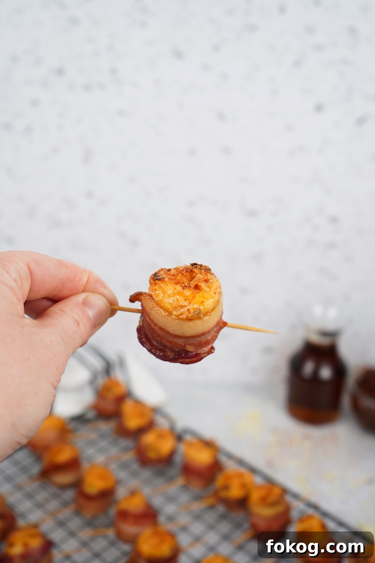 Smoked pig shots on toothpick in hand. 