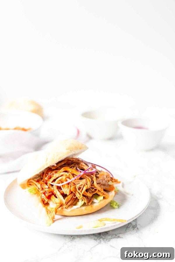 Instant Pot Pulled Pork Sandwich. Juicy and soft pulled pork smothered in a thick barbecue sauce. Served on a Kaiser roll with lettuce.