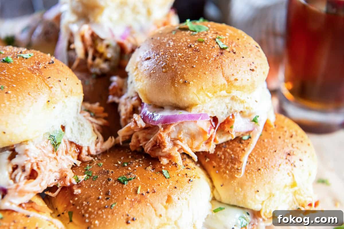 BBQ chicken slider stacked with glasses of beer next to them.