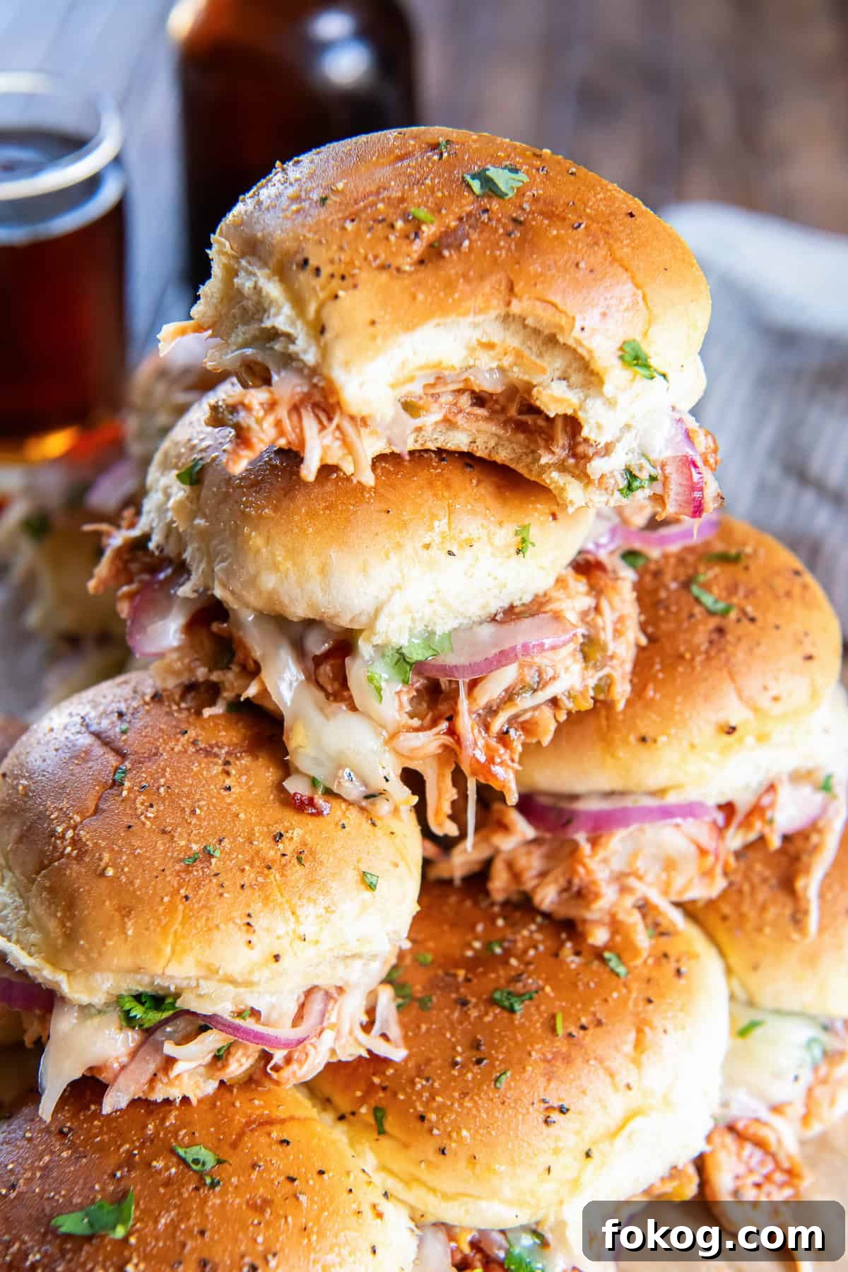 A stack of BBQ chicken sliders with a bite missing from the one on top.
