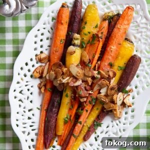 roasted glazed carrots with sliced almonds on a white serving platter with a cut-out pattern around the edges.
