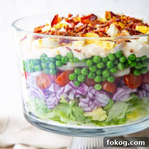 7 layer salad in a glass trifle dish.