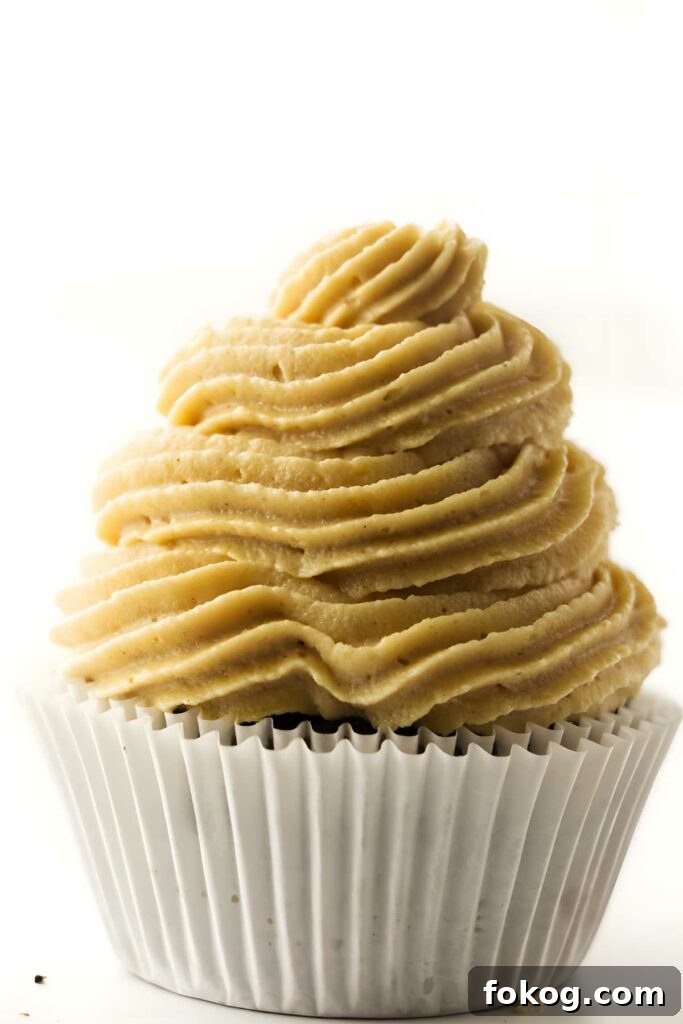 Close-up of cupcake with light brown frosting in white paper liner.