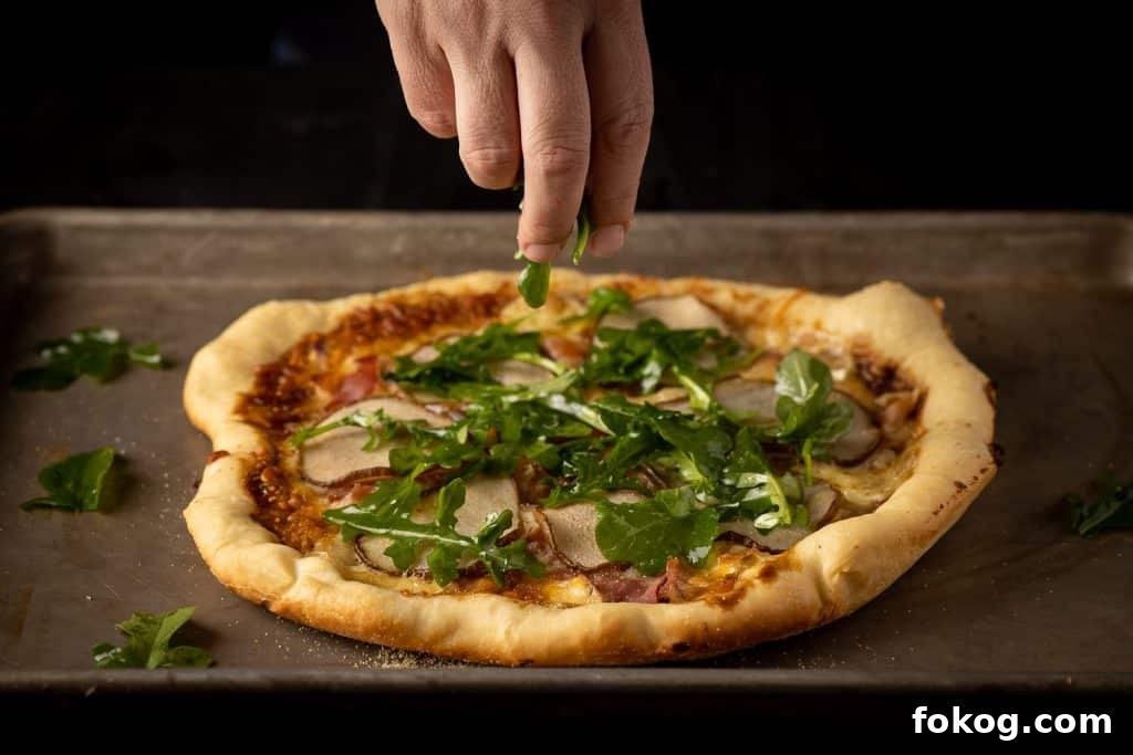 Arugula being sprinkled on top of a Dutch oven pizza.