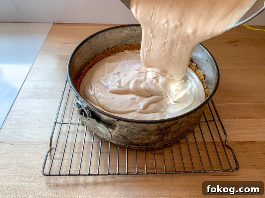 A cheesecake batter being poured into a pan. 