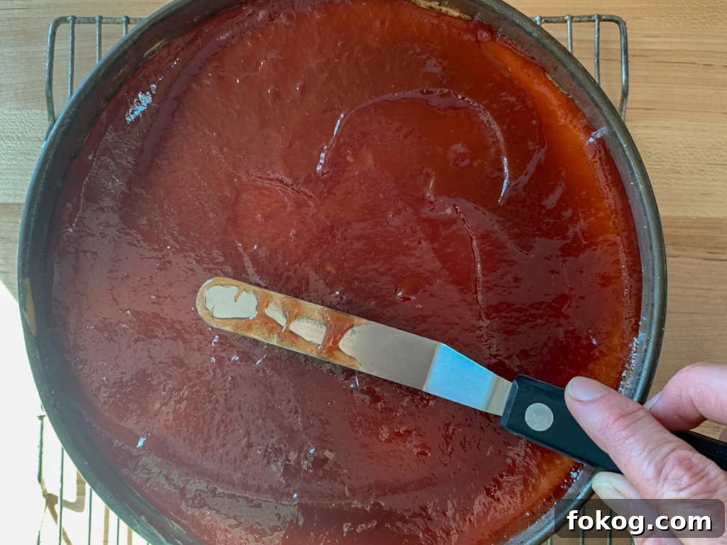A hand spreading guava jelly on top of a cake. 