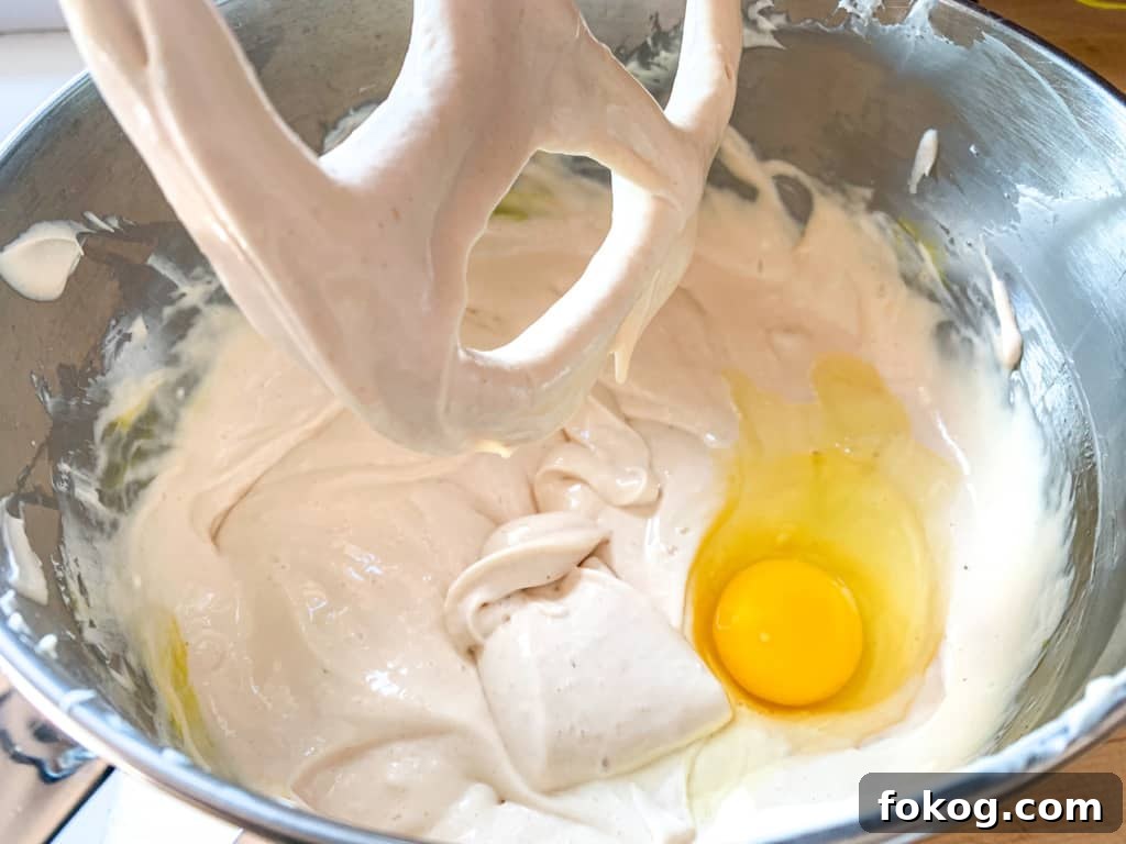 A mixing bowl with cream cheese and an egg in it. 