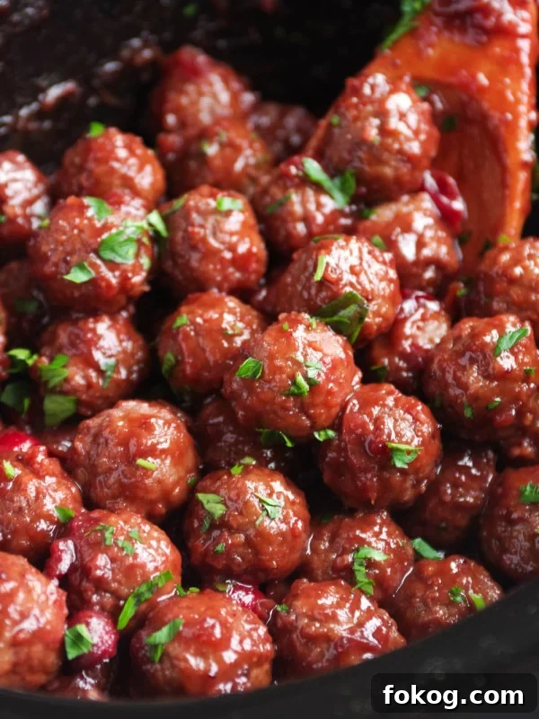 Cranberry sauce covered meatballs in a slow cooker.