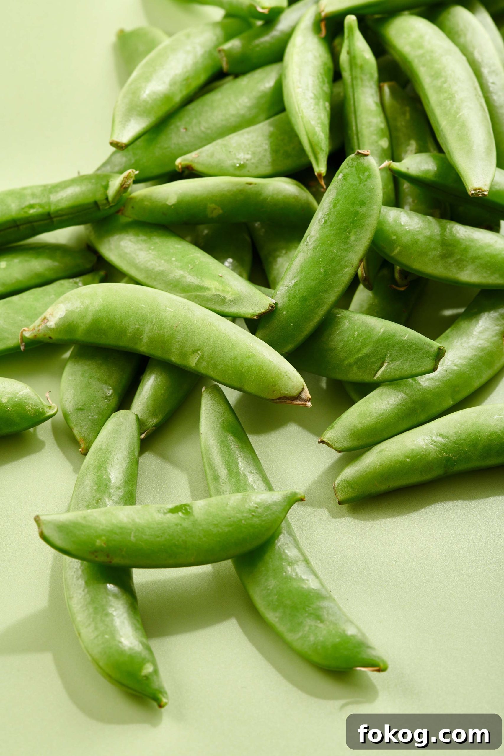 Sugar Snap Peas on a light green surface.