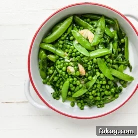 Green peas, sugar snap peas, garlic, arugula, and spinach in white bowl.