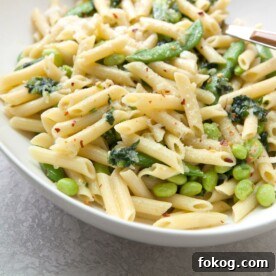 Pasta with Ramps, Edamame, and Sugar Snap Peas in a Light Parmesan Cream Sauce in white bowl.