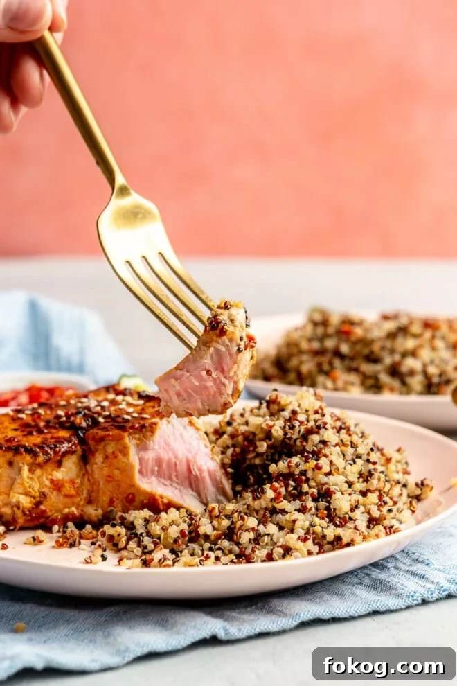 Chili-Lime Seared Ahi Tuna with Cilantro-Lime Sauce 10 A person using a fork to get a bite of chili-lime seared ahi tuna steak.