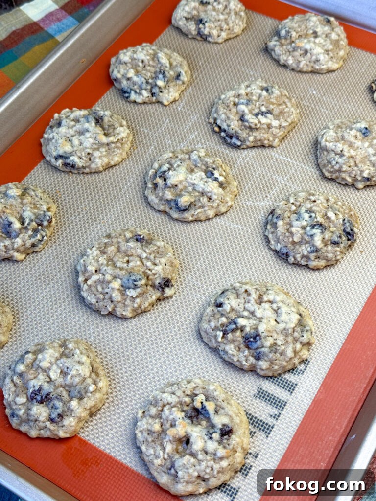 Warm and hearty oatmeal raisin cookies made with shortening on a lined baking sheet.
