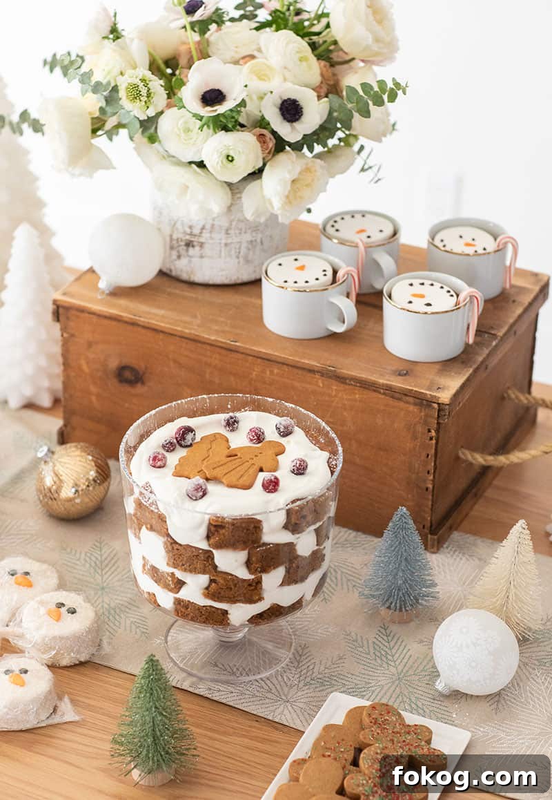 Christmas desserts on a table with bottle brush trees, gingerbread trifle, ornaments, hot coco.
