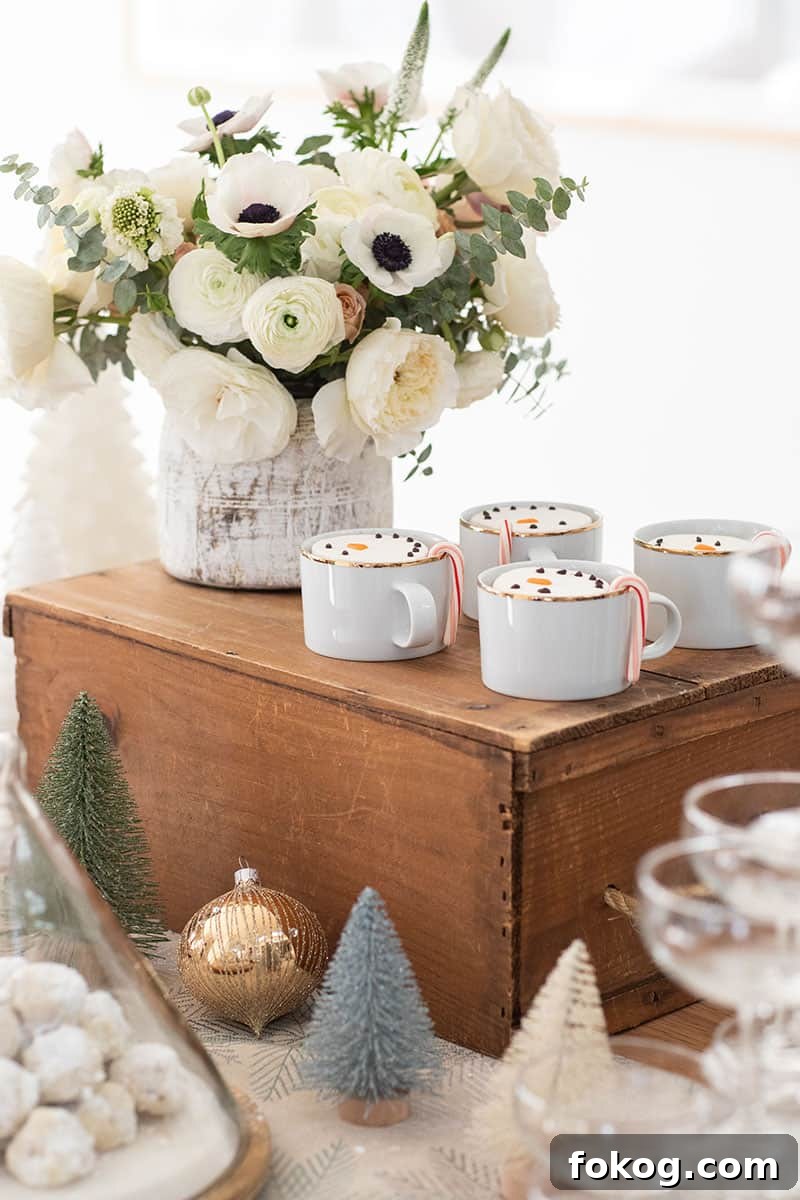 White flowers and gold cups filled with hot chocolate and snowman marshmallows. 