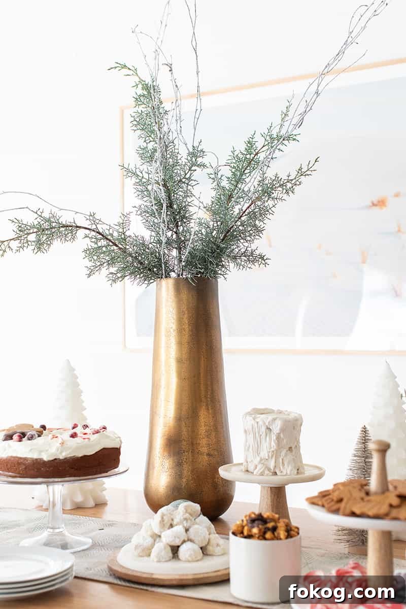 Tall brass vase with green and white branches.
