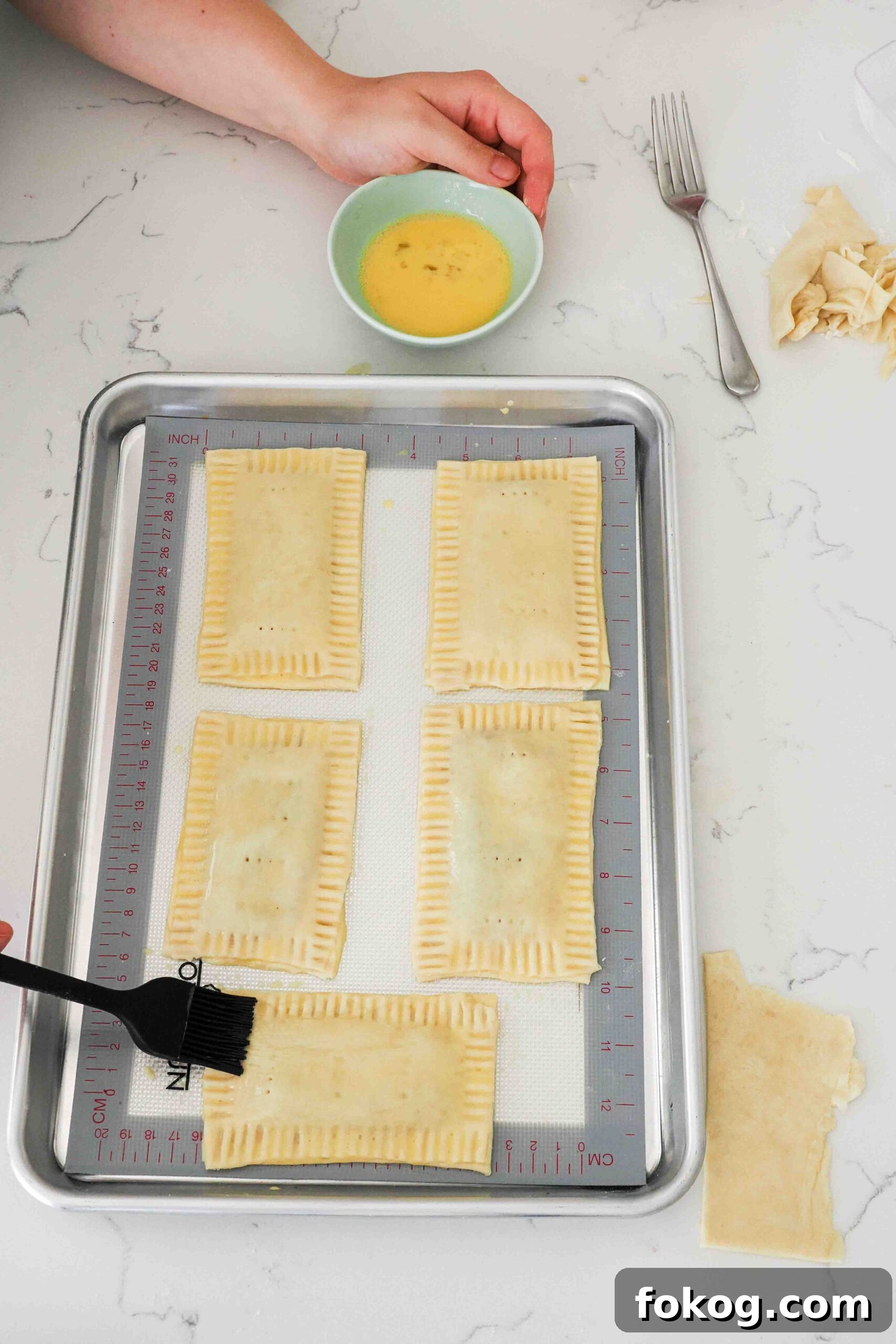Egg wash is brushed onto homemade pop tarts with a pastry brush.