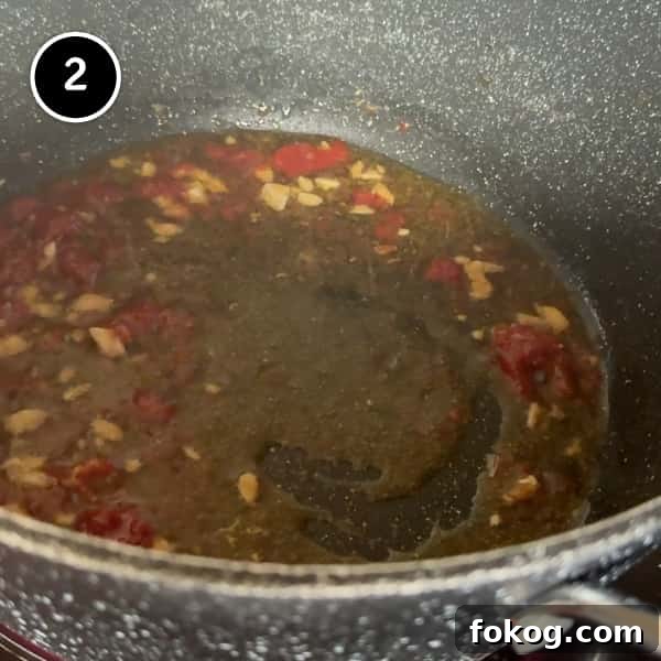 Pasta e Ceci – Italian Pasta with Chickpeas | cookeatworld.com frying garlic, anchovies and tomato paste in a pot