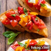 Three bruschetta slices on a wooden cutting board with fresh basil leaves.