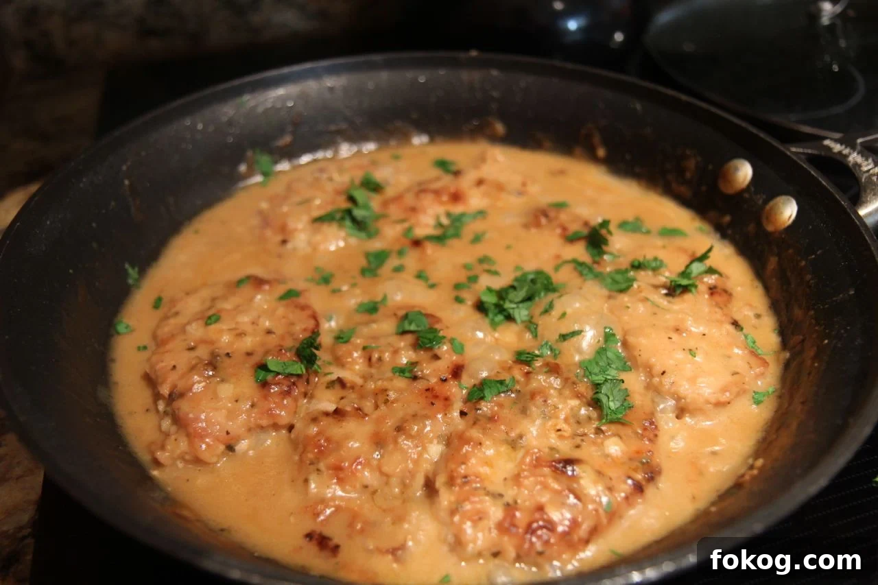 smothered pork chops, parsley, in a black skillet. 