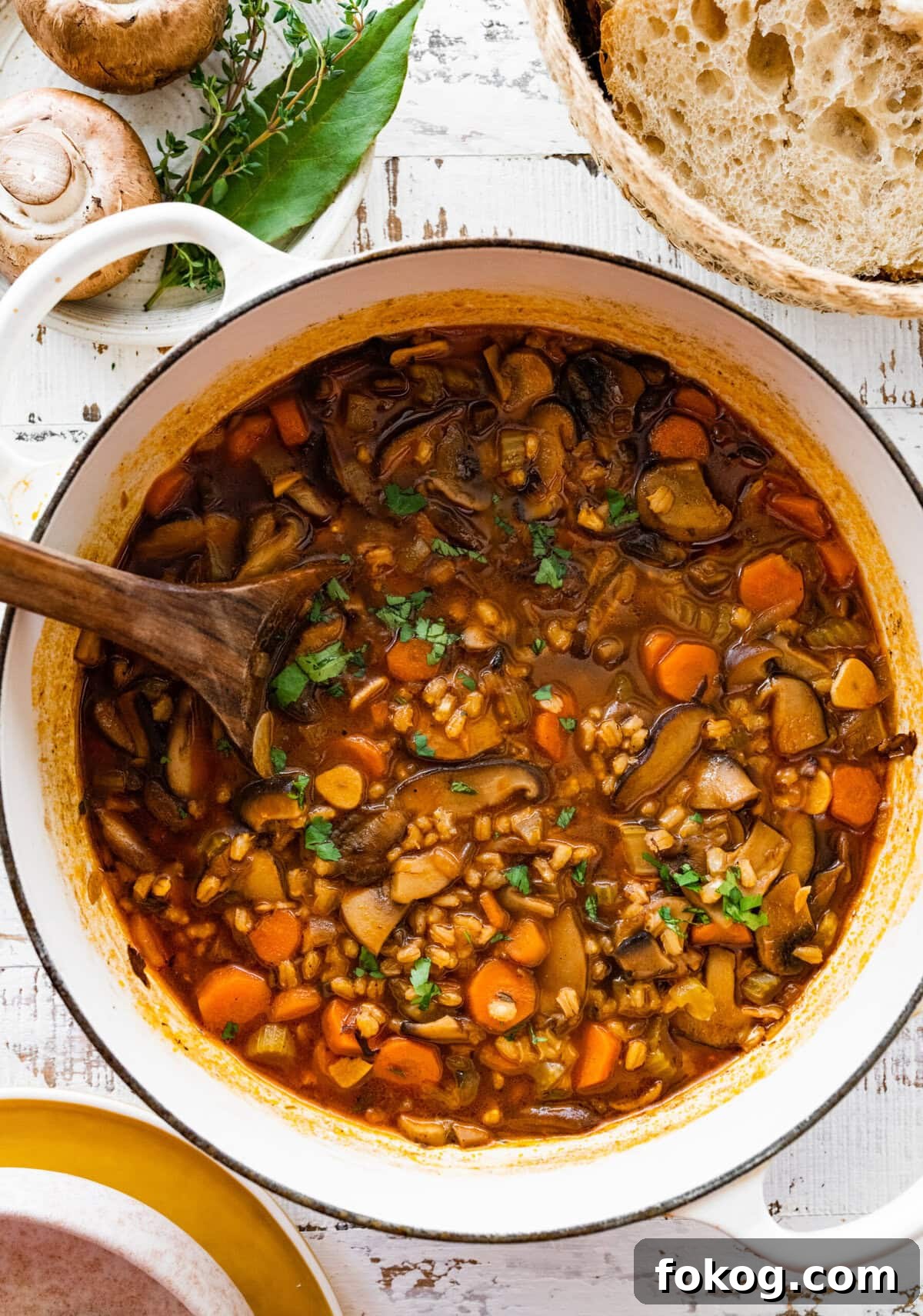 Dutch oven of mushroom barley soup with a wooden spoon.