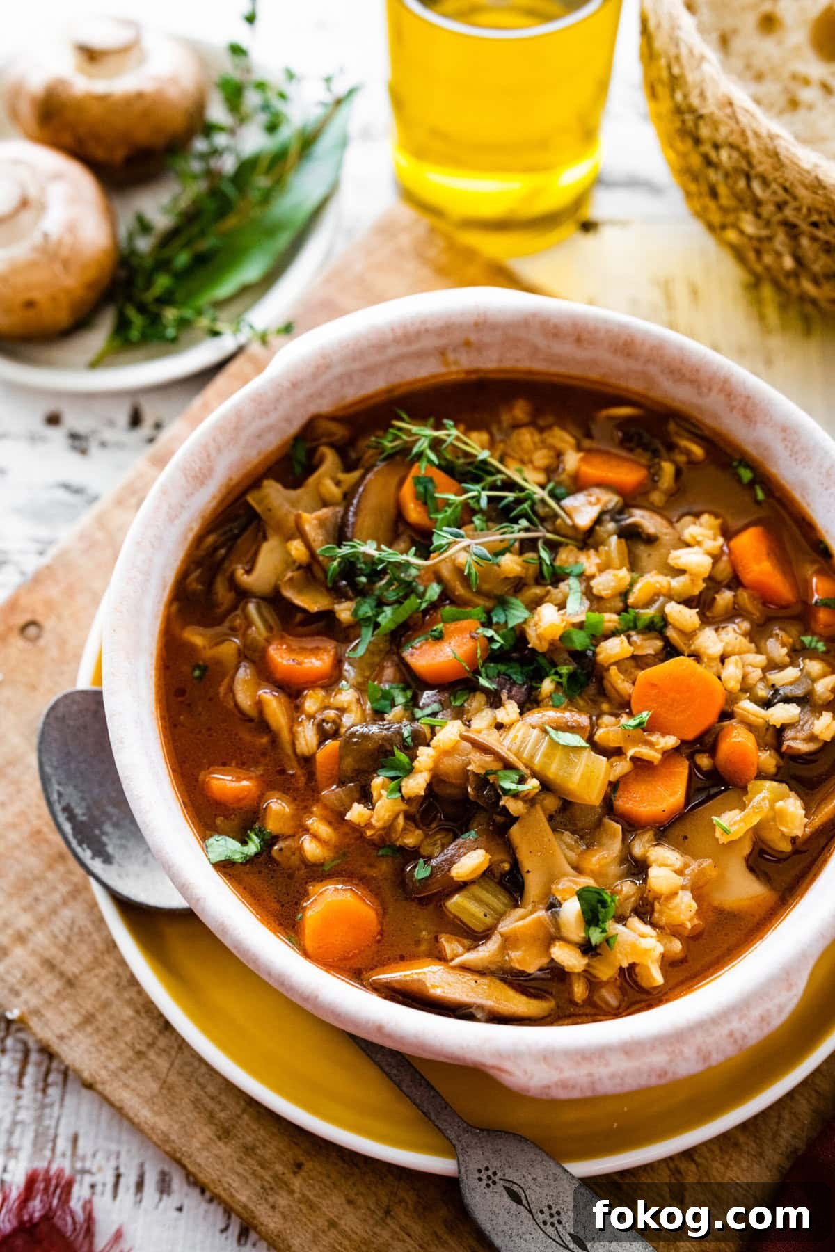 Bowl of mushroom barley soup topped with herbs.