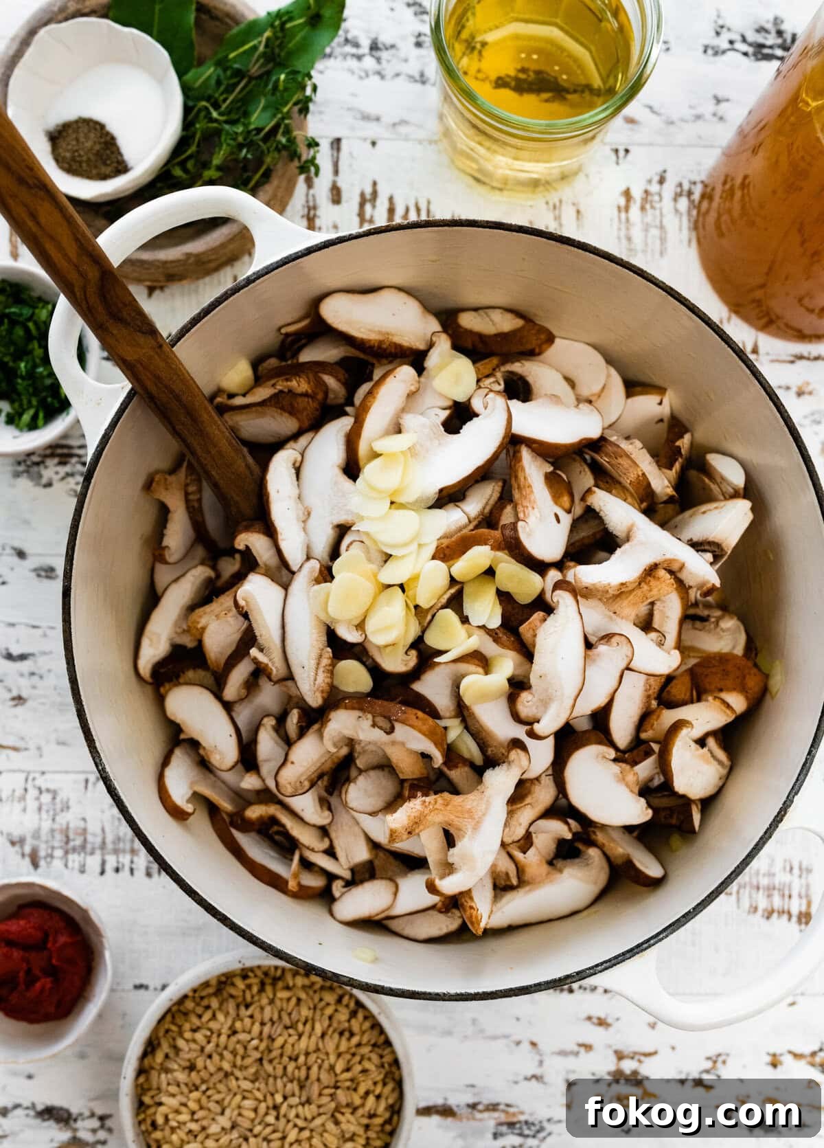 Spoon in a Dutch oven of mushrooms and garlic.