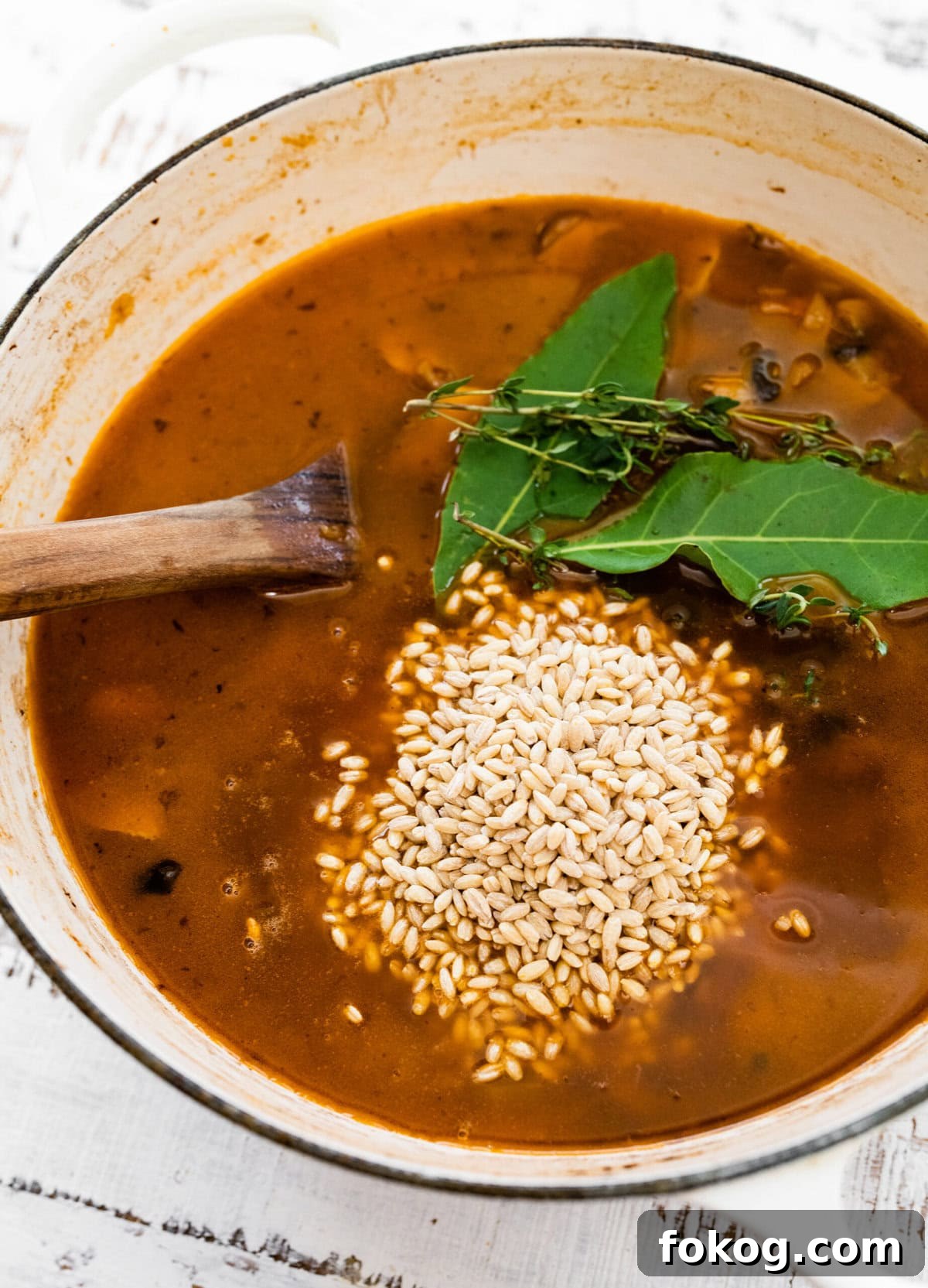 Barley and herbs in a Dutch oven of soup.