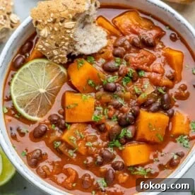Top-down shot of sweet potato chili in a white bowl with lime granish