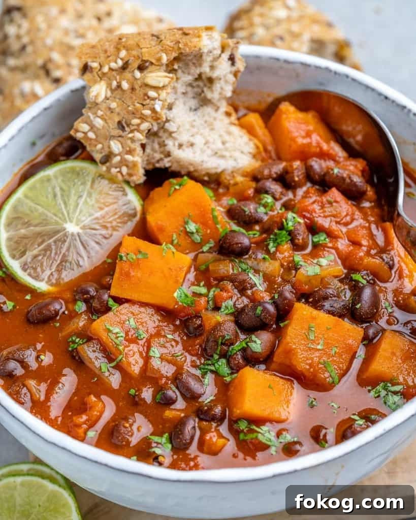 Bread in a bowl of sweet potato chili with lime garnish