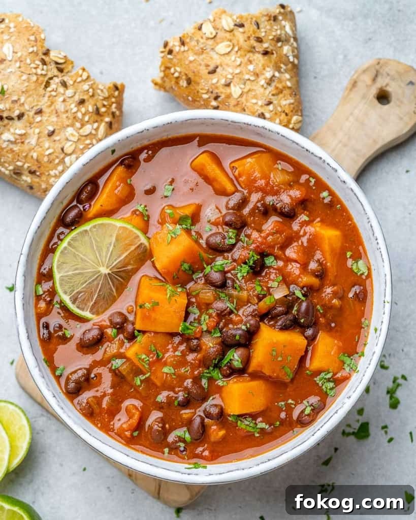 Overhead view of sweet potato chili in a  white bowl. with bread next to the bowl