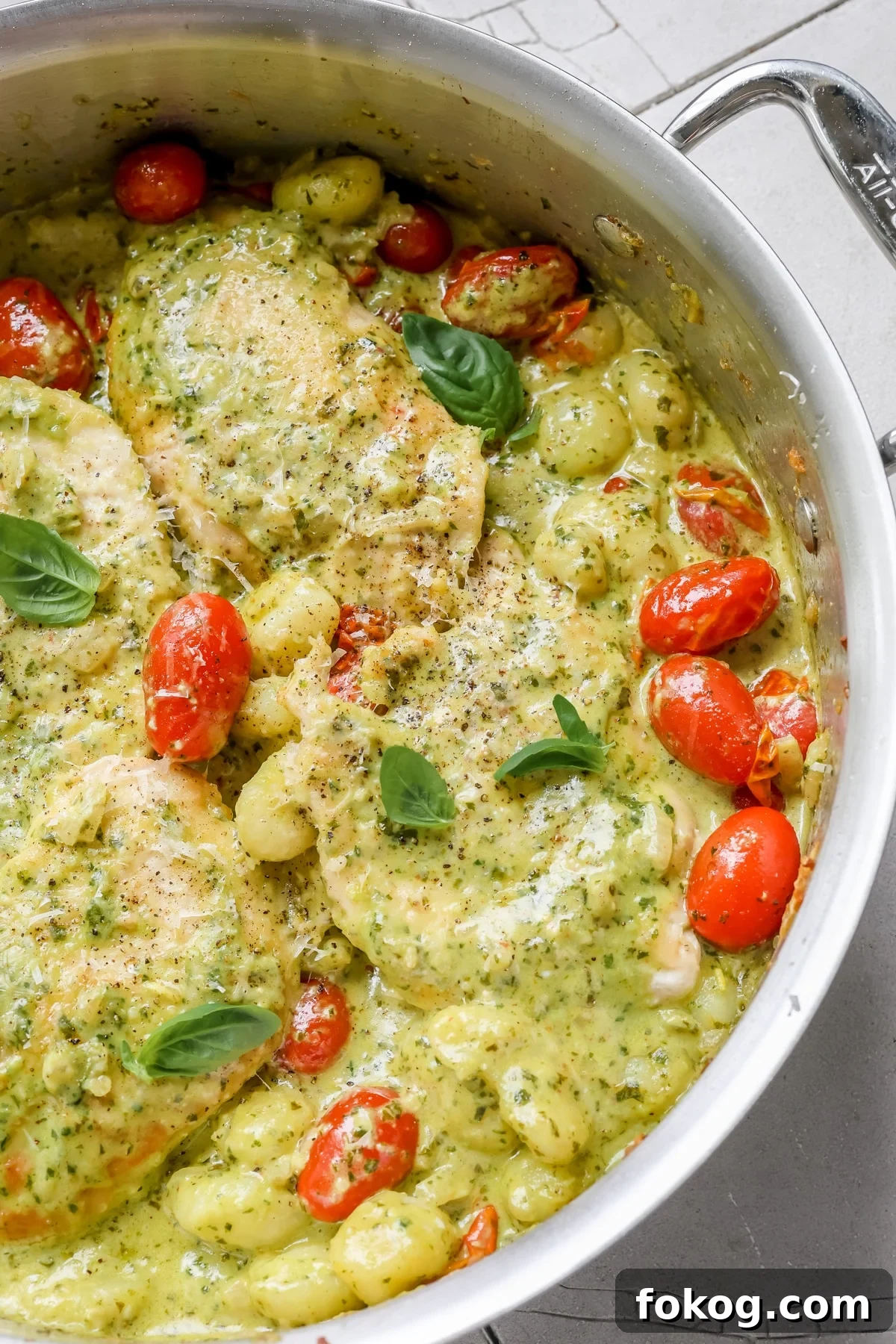 chicken, pesto and gnocchi in a skillet garnished with basil and black pepper.