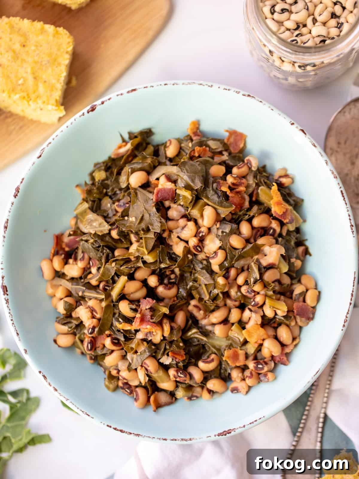 Instant Pot Black Eyed Peas and Greens Bowl of Instant Pot Black Eyed Peas and Collard Greens next to cornbread and dried beans.