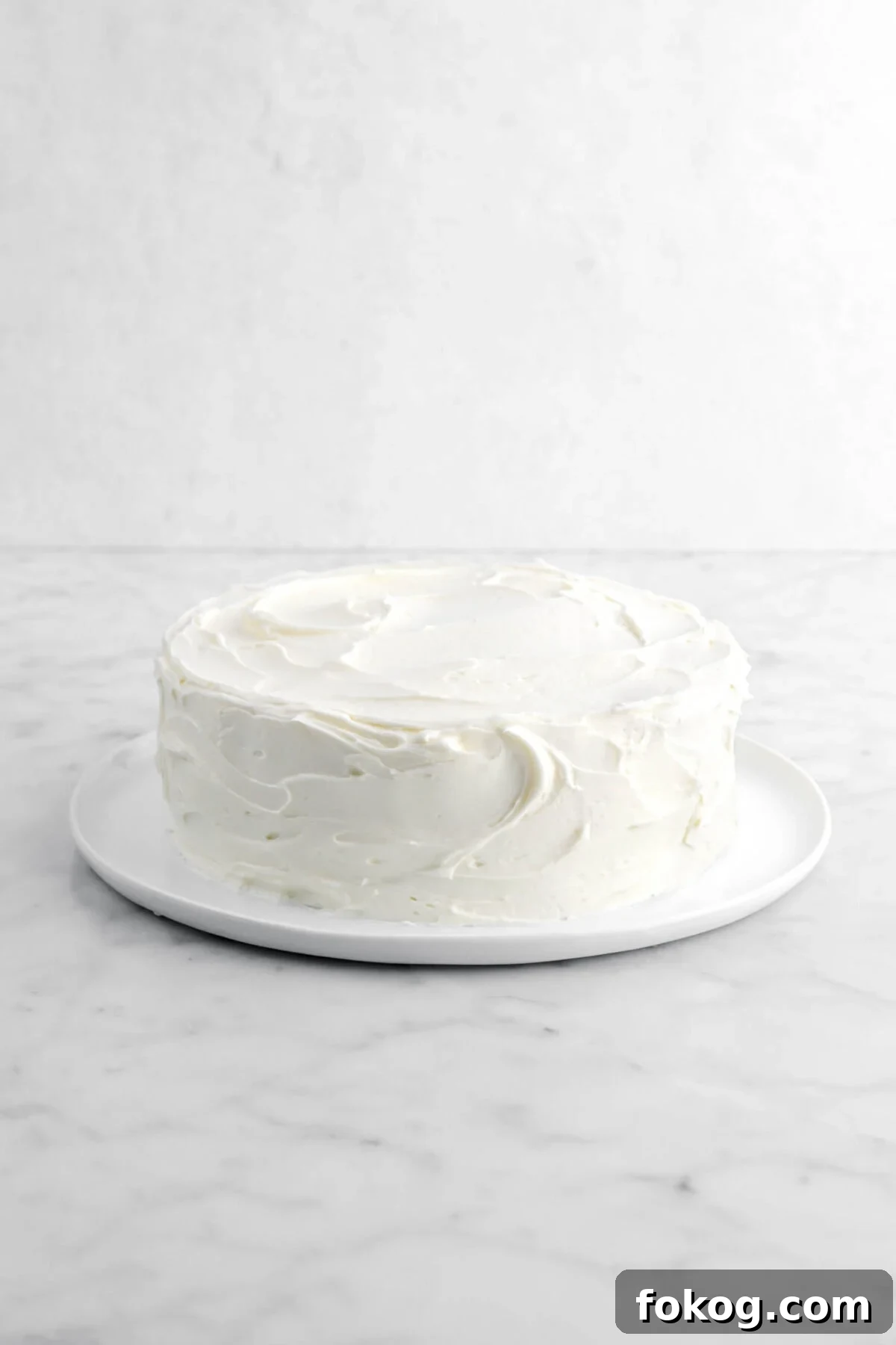 Classic Vanilla Cake with Smooth Buttercream Frosting 17 frosted cake on white plate.