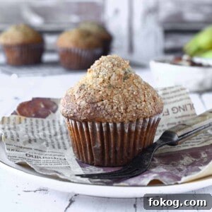 Moist Banana Pecan Muffins Recipe for Breakfast or Brunch 12 Close-up of a banana muffin on a white plate with muffins in the background.