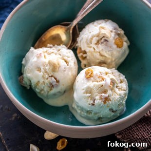 3 scoops of white color ice cream served in a blue bowl with 2 golden spoons placed on the side