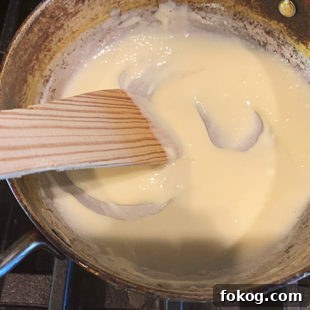 spatula stirring milk powder and cream in a pan