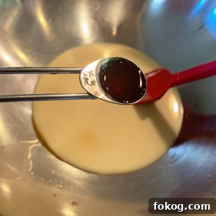 vanilla extract being added to a bowl of condensed milk