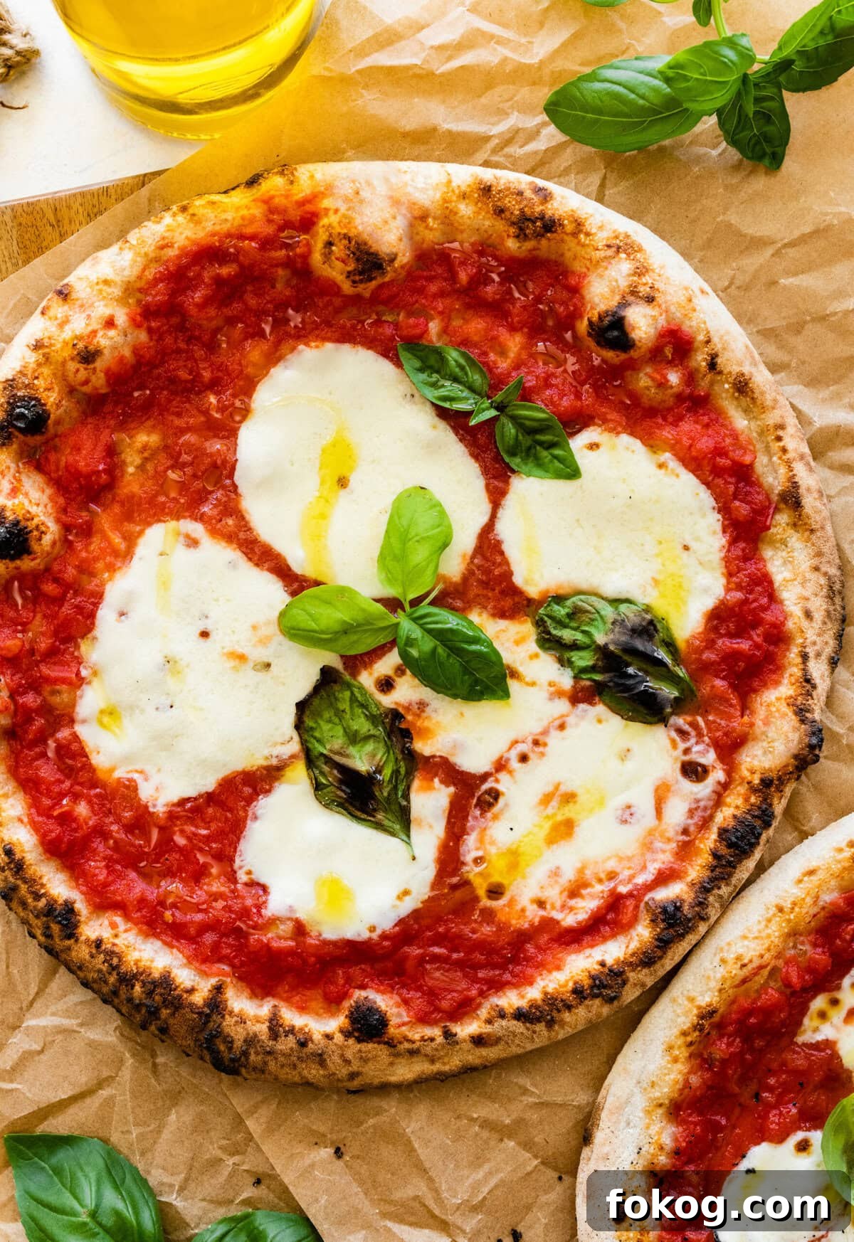 Two pizzas with mozzarella cheese (margherita pizza) and basil leaves