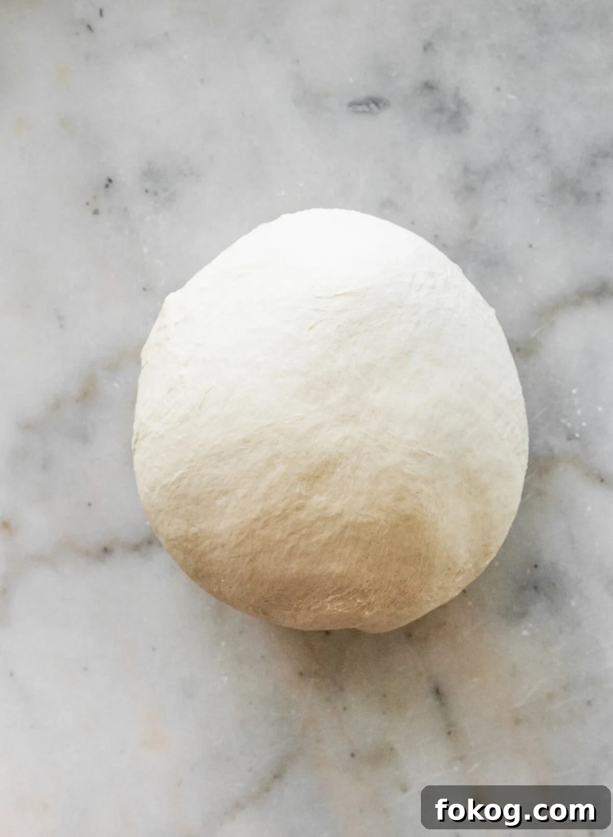 A ball of dough on a marble counter.