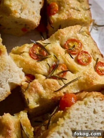 Slices of focaccia topped with cherry tomatoes on white parchment paper.