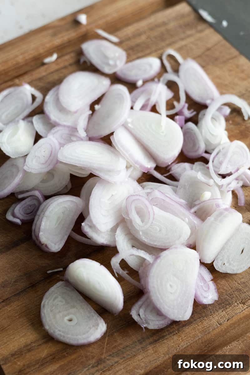 Sliced shallots on a wooden cutting board. 