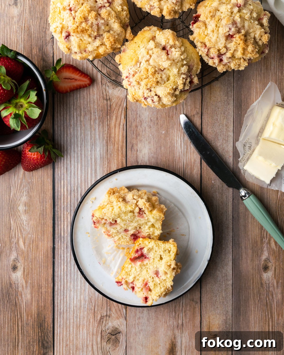Gluten-Free Strawberry Muffins Recipe with Moist, Tender Crumbs 2 Gluten free strawberry muffins on a cooling rack sitting on a wooden table.